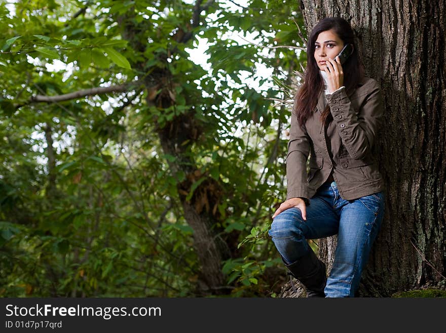 Young woman talking by phone on deep forest great space for copy. Young woman talking by phone on deep forest great space for copy