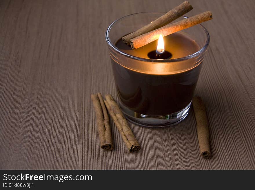 Candle and Cinnamon against the Wooden Surface