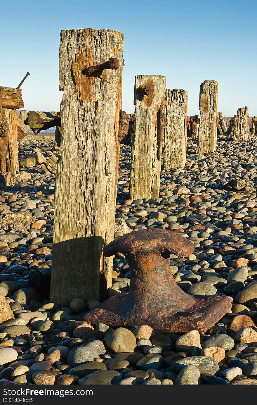 Weathered groynes (sea-defences) and a rusty old bollard. Weathered groynes (sea-defences) and a rusty old bollard