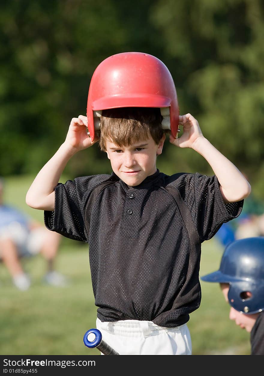 Little Boy Putting on Helmet Getting Ready to Hit. Little Boy Putting on Helmet Getting Ready to Hit