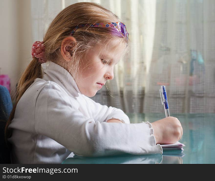 Small girl is writing with a pen