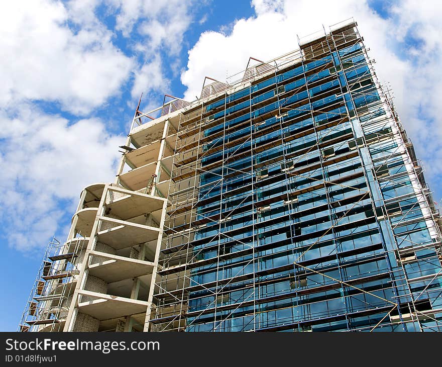 High building of glass and concrete on a blue sky background. 
under construction. High building of glass and concrete on a blue sky background. 
under construction