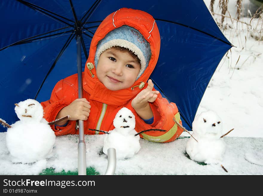 Child in red overalls on background of the blue umbrella