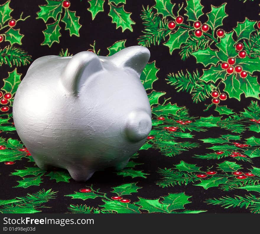 Silver piggy bank on a holy pattern fabric background. Silver piggy bank on a holy pattern fabric background.