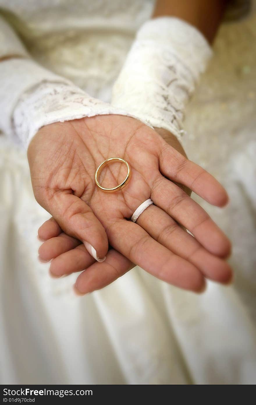 Hispanic bride's hands holding groom's wedding band, shallow dof. Hispanic bride's hands holding groom's wedding band, shallow dof