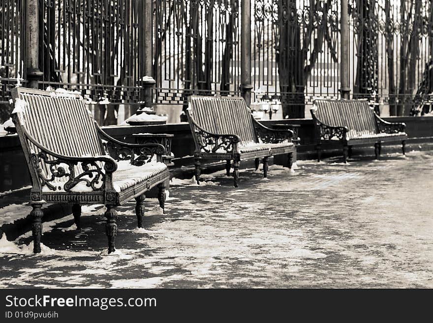 Black and white image of three benches in a park