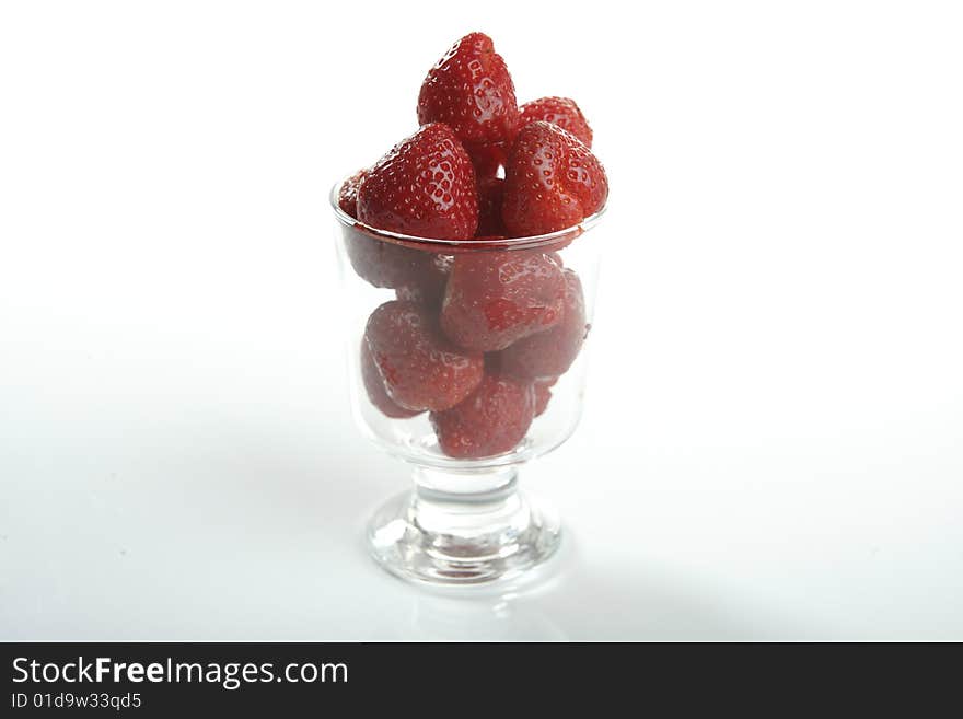 Glass cup full of strawberries in studio white background. Glass cup full of strawberries in studio white background