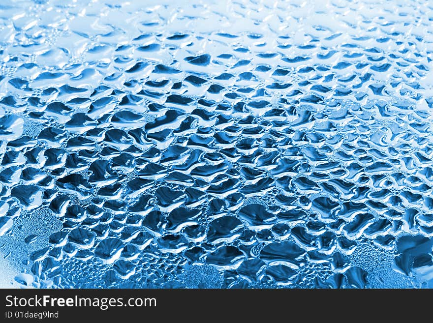 Blue water drops on glass. Pure water background.