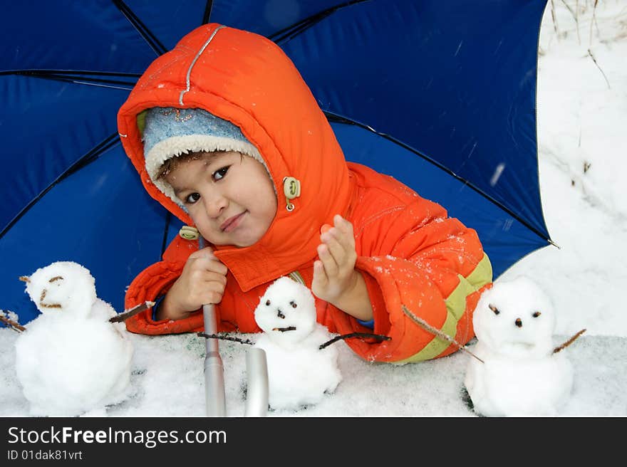 Child in red overalls on background of the blue umbrella