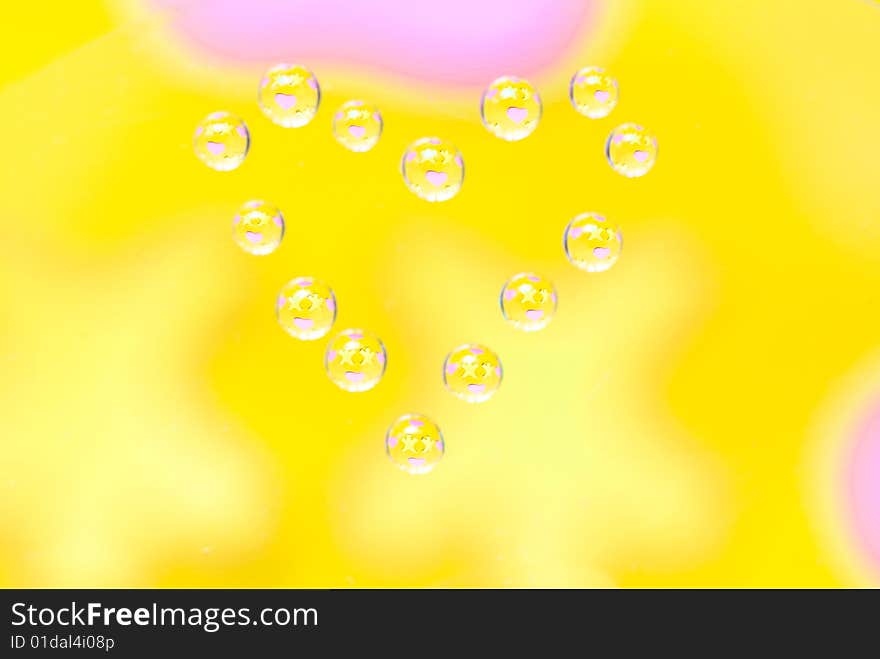 Water drops in the form of heart on a multi-coloured celebratory background