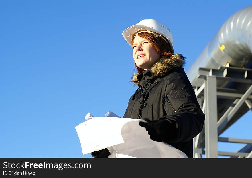 Young architect looking at blueprint against sky