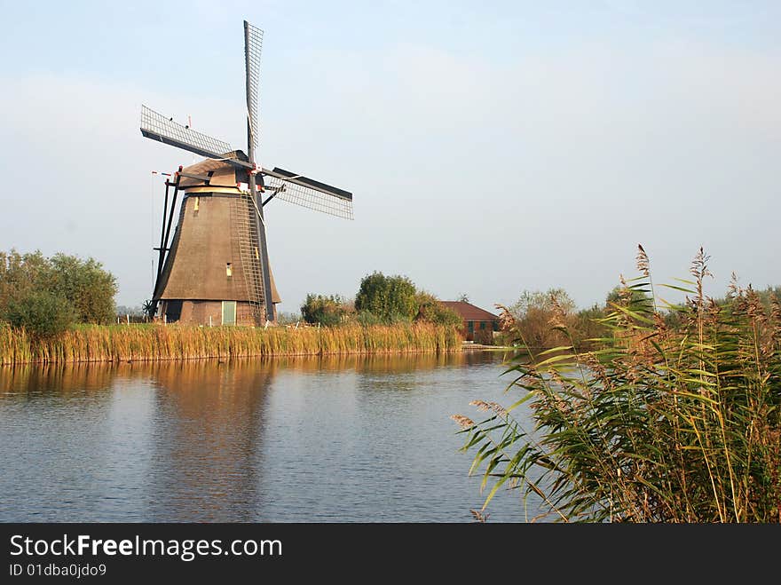 Scenic view of traditional Dutch windmill with canal in foreground, Kinderdijk, Netherlands. Scenic view of traditional Dutch windmill with canal in foreground, Kinderdijk, Netherlands.