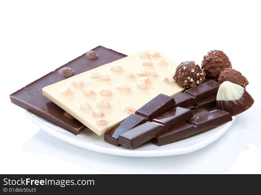 Bars of white and black chocolate, sweets lying on plate, isolated. Bars of white and black chocolate, sweets lying on plate, isolated