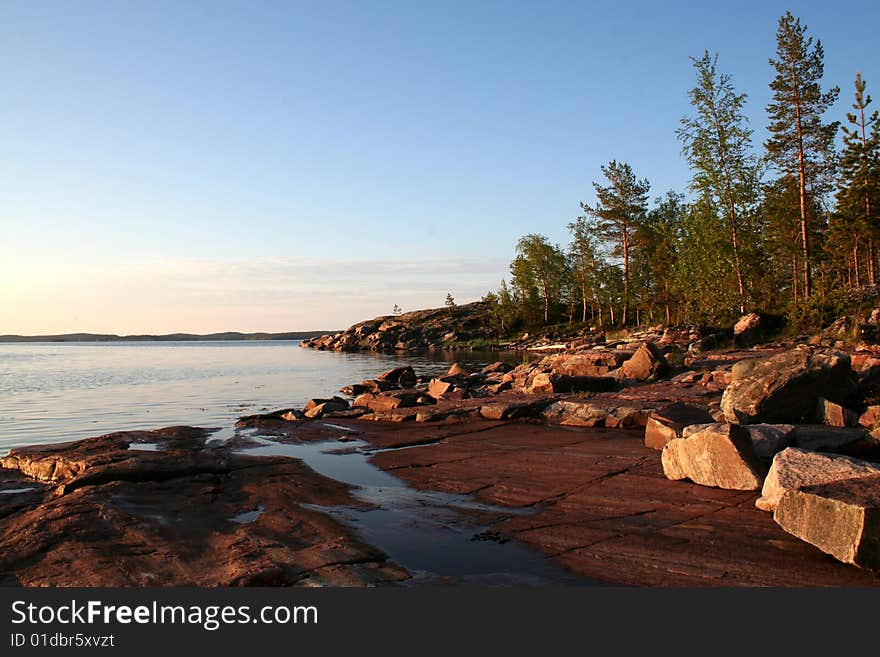 Summer sunrise with forest, water and rocks