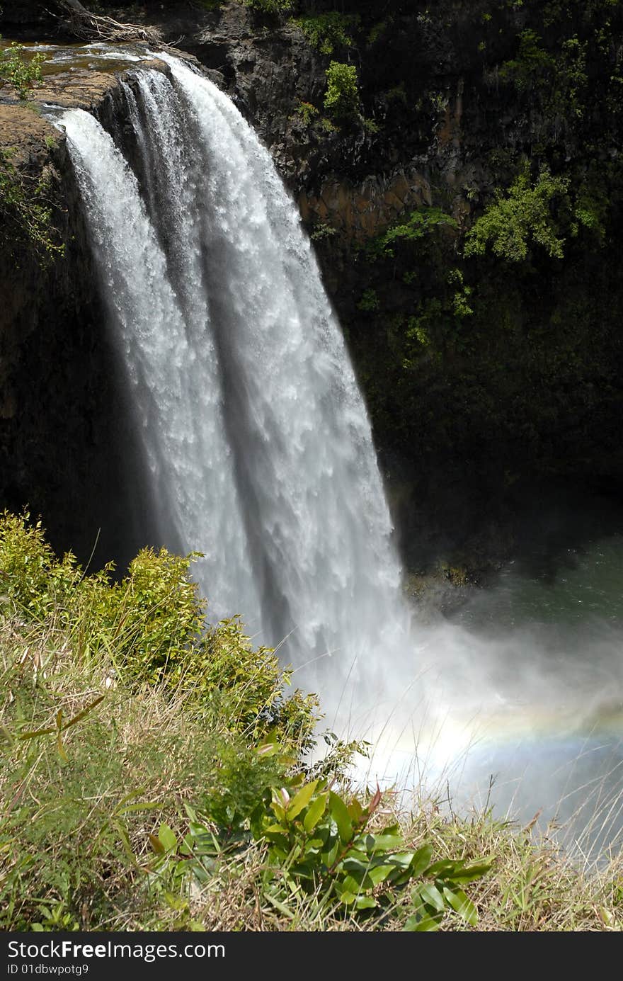 A waterfall in Hawaii with a rainbow at its base. A waterfall in Hawaii with a rainbow at its base