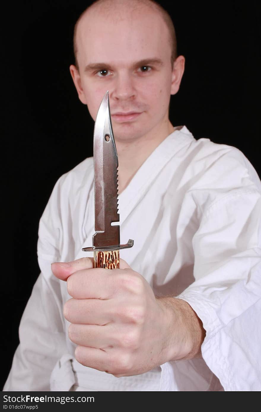 Man in kimono on black background with knife. Man in kimono on black background with knife