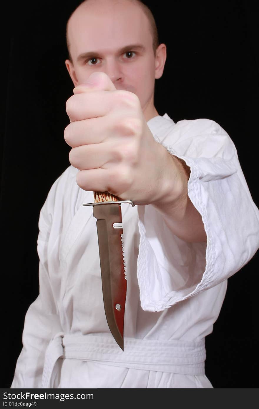 Man in kimono on black background with knife. Man in kimono on black background with knife