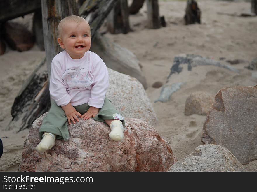 Beautiful child sits on  stone at  sea. Beautiful child sits on  stone at  sea