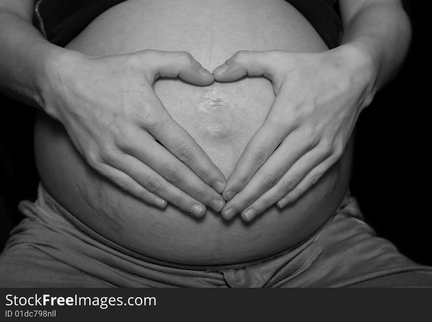 Heart shape made with hands on pregnant belly. Heart shape made with hands on pregnant belly