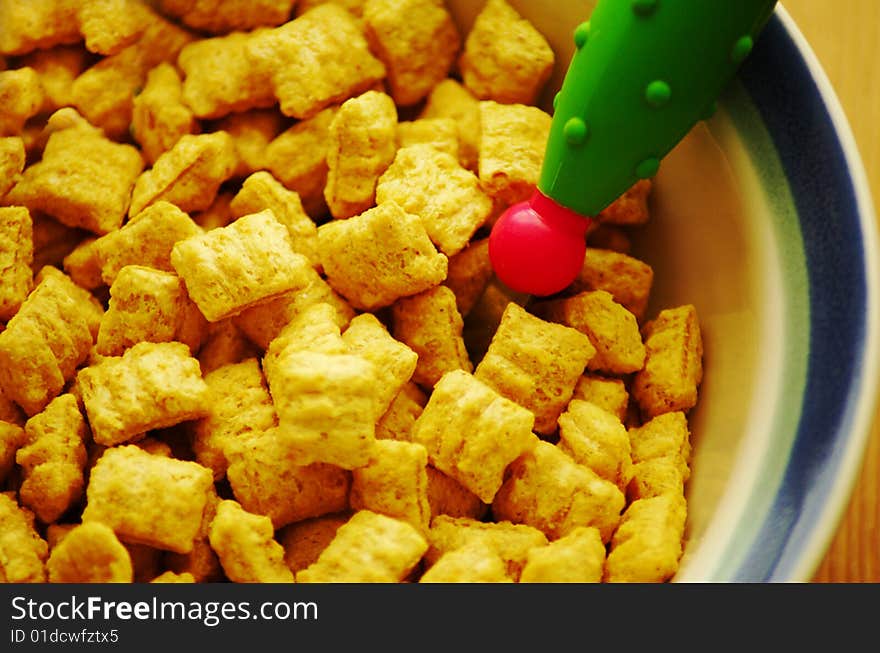 Close up of bowl with cereal and rubber spoon on blue background. Close up of bowl with cereal and rubber spoon on blue background.