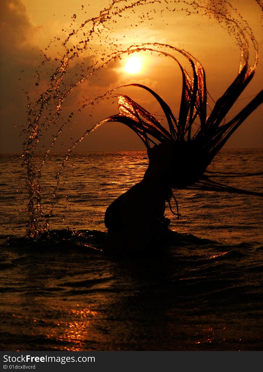 Girl in a water at sunset with long hair and water drops. Girl in a water at sunset with long hair and water drops