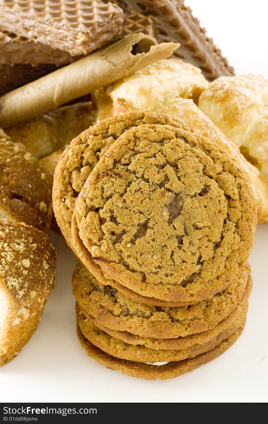 Sweet cookies one over another next to a lot of desserts on white bakcground