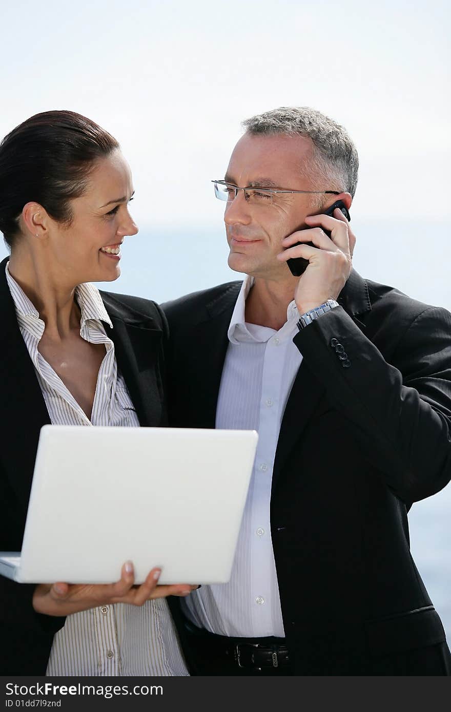 Businessman with mobile phone and businesswoman with laptop computer. Businessman with mobile phone and businesswoman with laptop computer