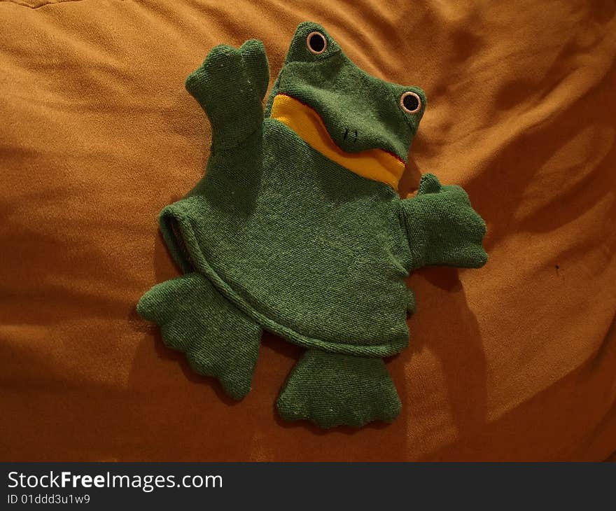 Green plush frog on pillow