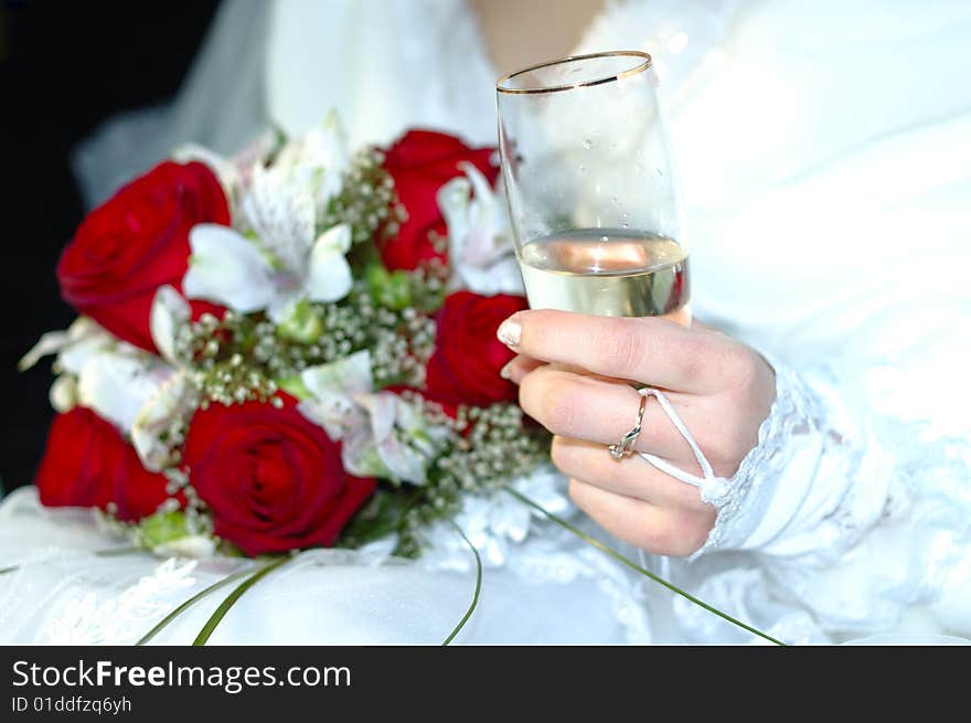 Bride with wedding bouquet and glass of champagne.