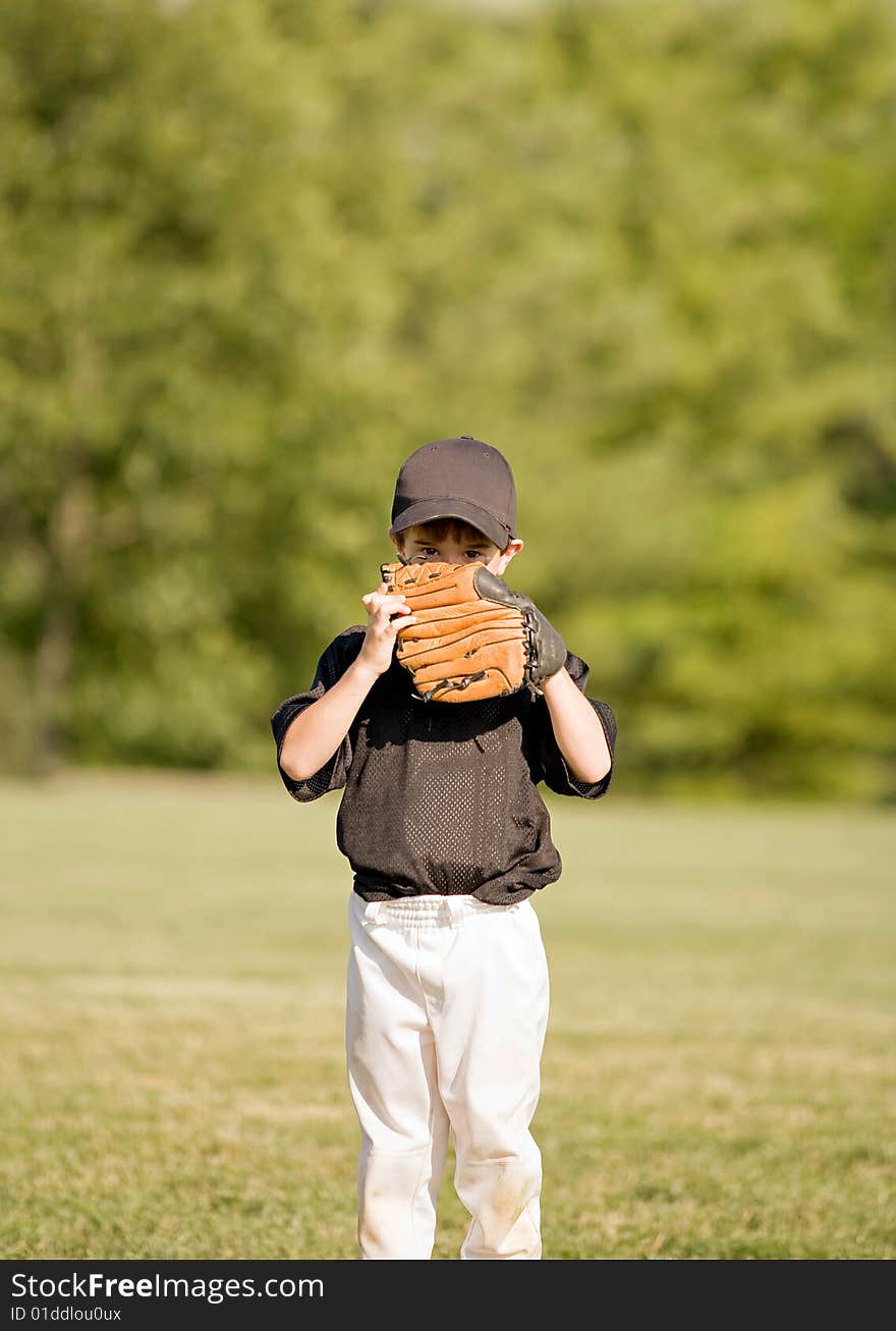 Little Boy Hiding Behind His Glove During a Baseball Game