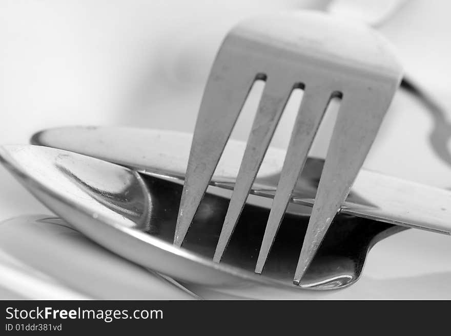 Detail of fork and spoon on white plate. Detail of fork and spoon on white plate