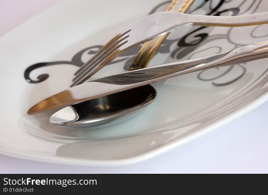 Detail of fork and spoon on white plate. Detail of fork and spoon on white plate