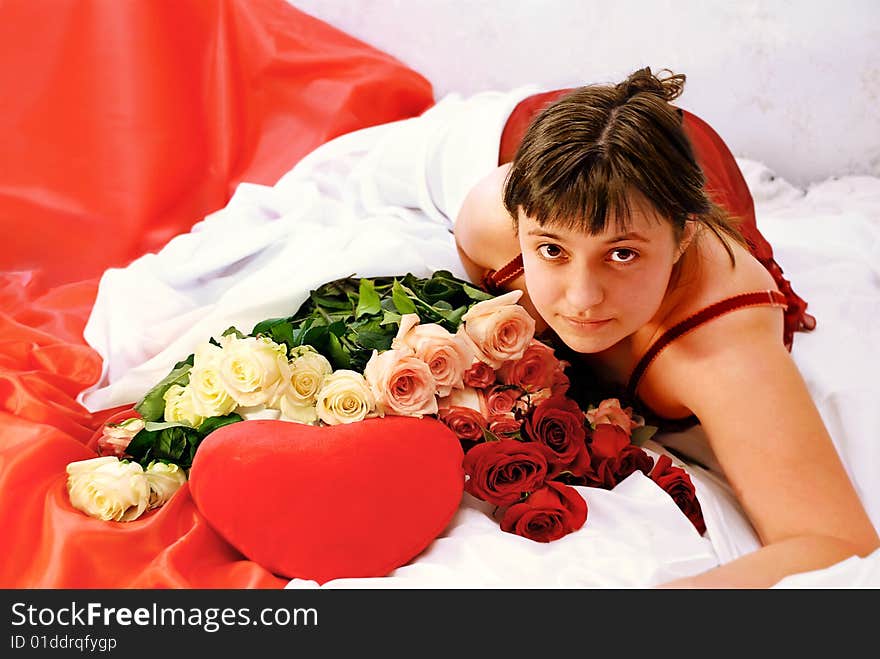 Girl, lying on beds, heart and roses with it alongside. Girl, lying on beds, heart and roses with it alongside.