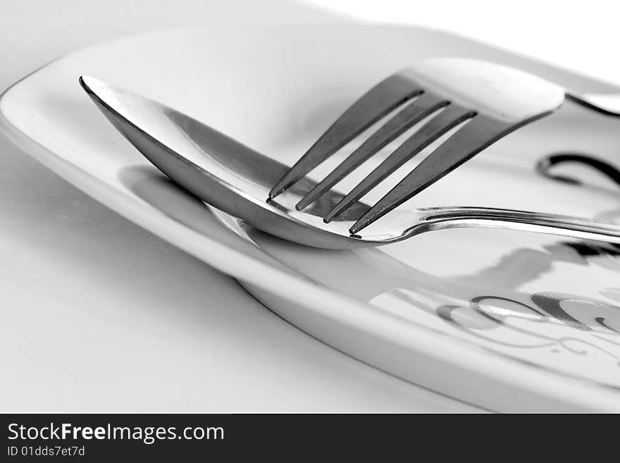 Photo of fork and spoon on white plate. Photo of fork and spoon on white plate