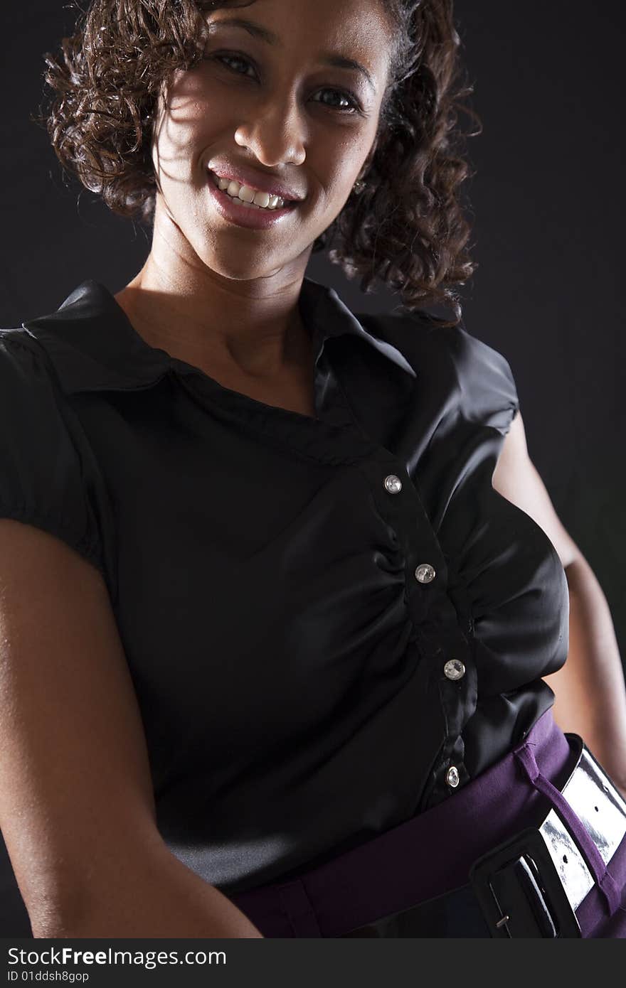 Young adult black woman with smile while leaning forward, backlit on black background. Young adult black woman with smile while leaning forward, backlit on black background.