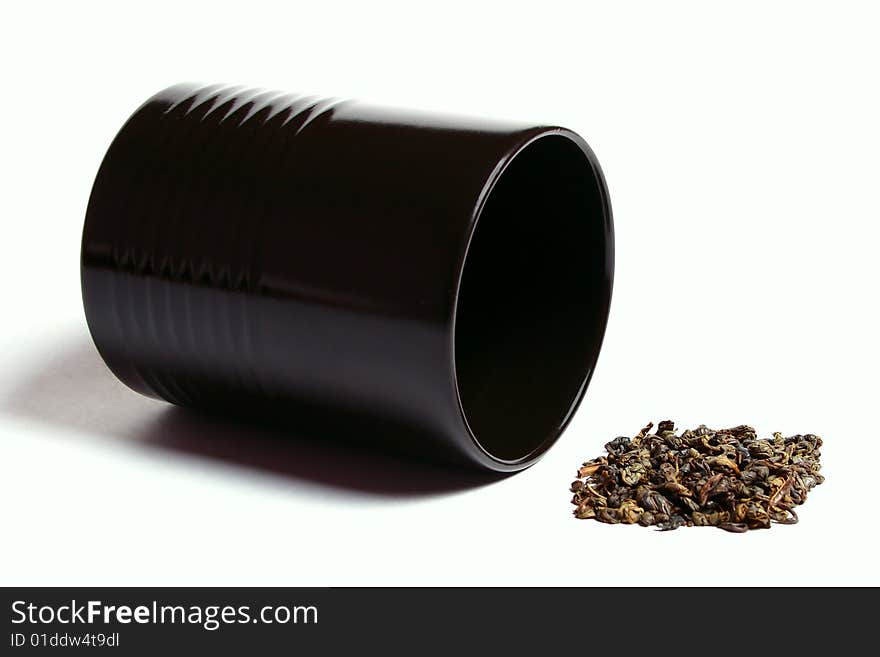 Black cup heap of green tea leaves isolated over white