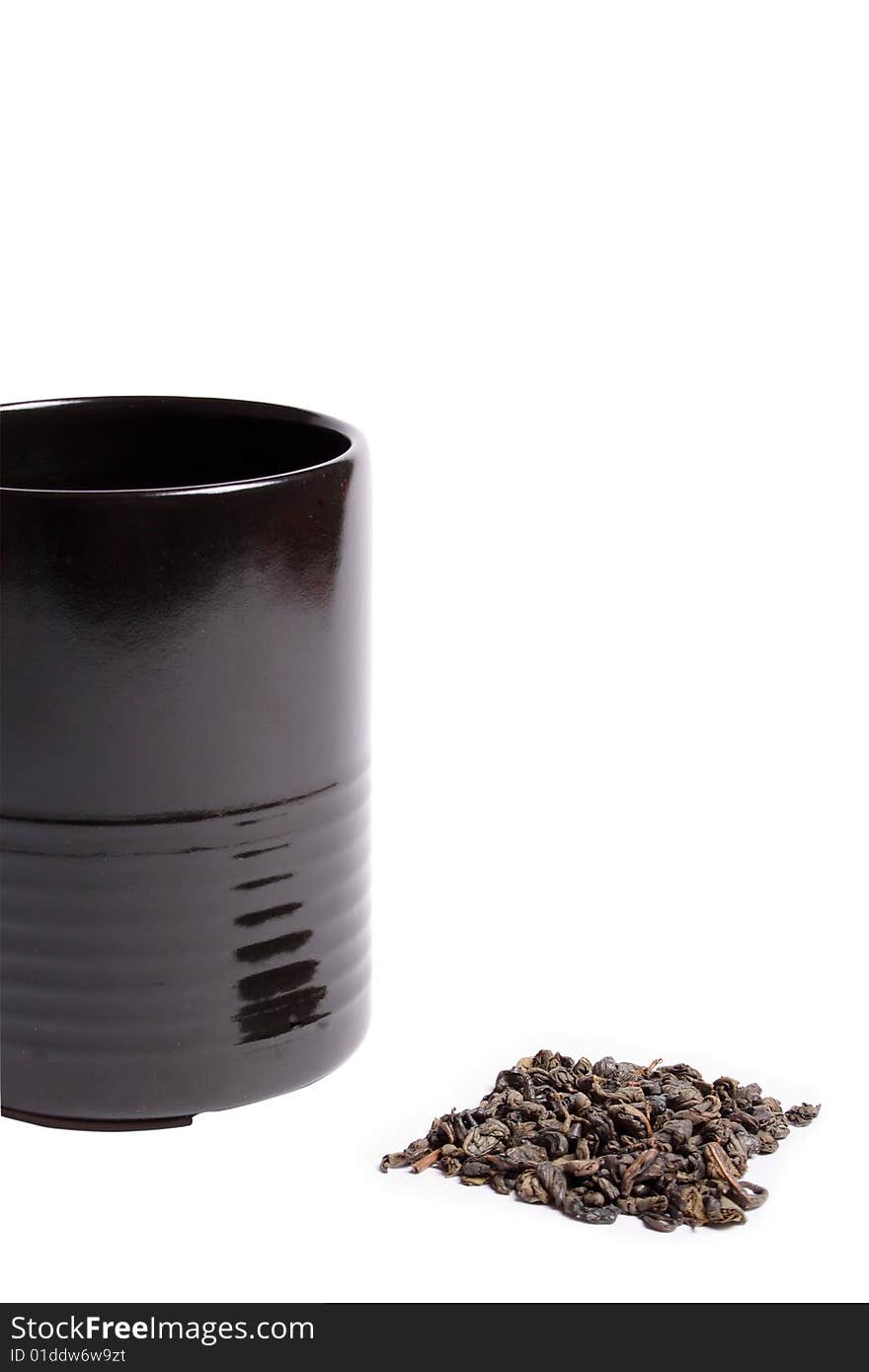 Black cup heap of green tea leaves isolated over white