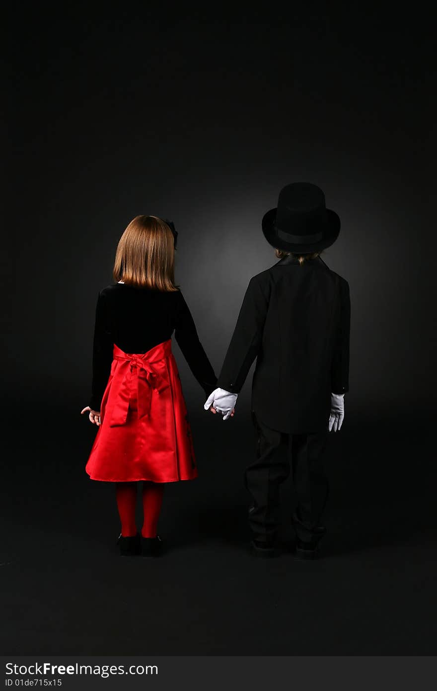 Boy and girl in formal clothing standing back to and holding hands. Boy and girl in formal clothing standing back to and holding hands