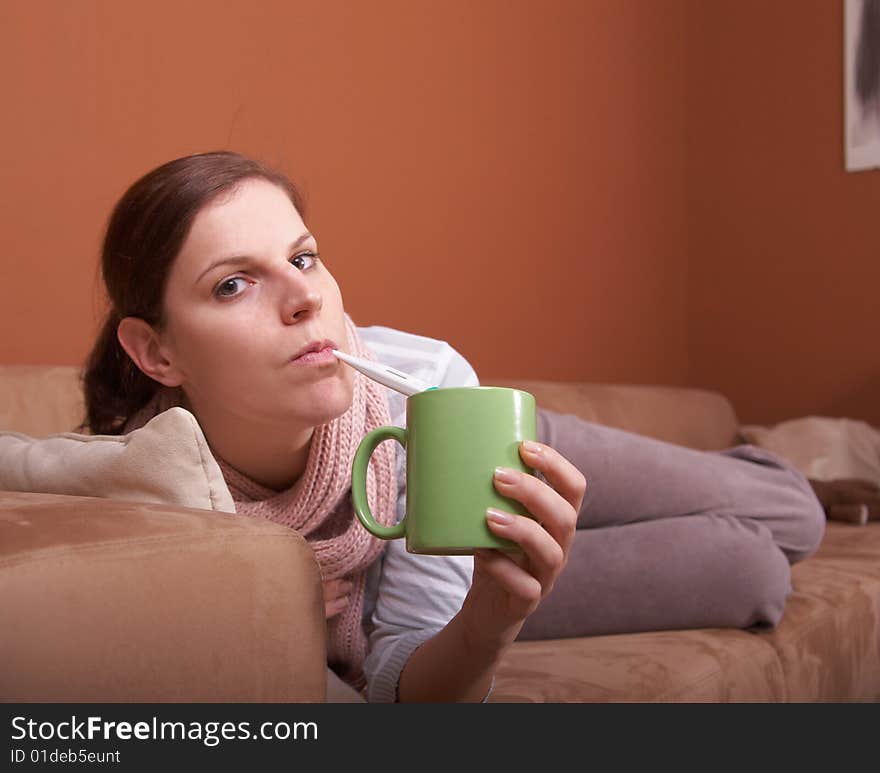 A young woman is sick. She is lying on the couch. She has a tea. A lot of copyspace. A young woman is sick. She is lying on the couch. She has a tea. A lot of copyspace.