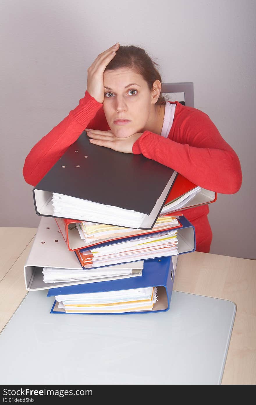 A young and beautiful female worker is stressed with a lot of paperwork in front of her. A lot of copyspace. A young and beautiful female worker is stressed with a lot of paperwork in front of her. A lot of copyspace.