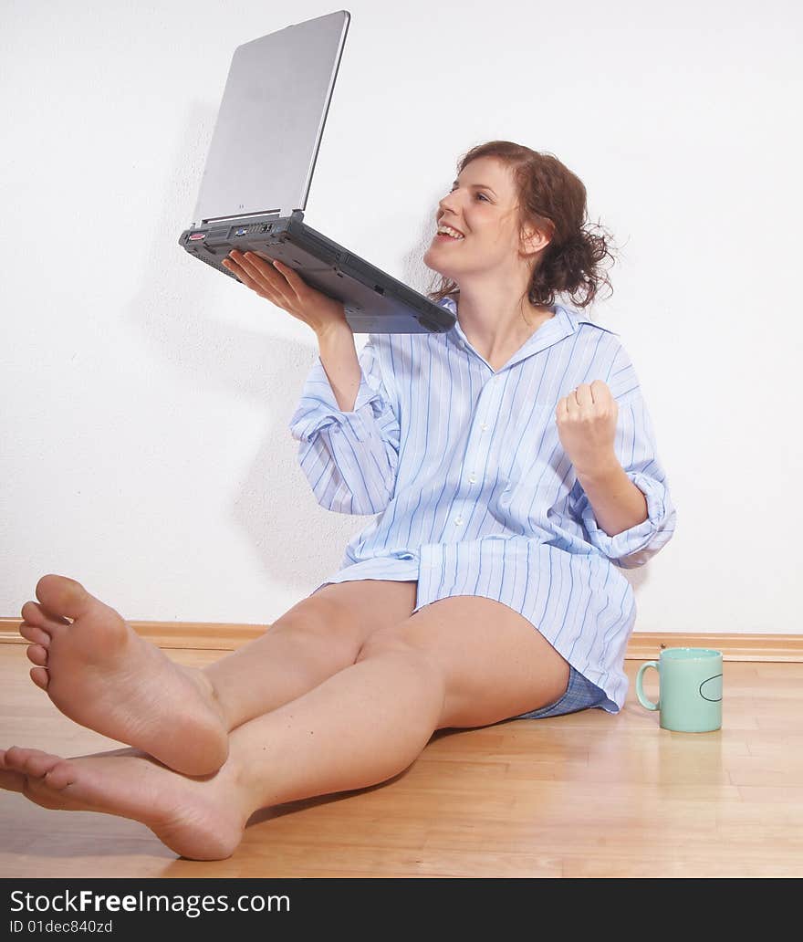 A young woman with a laptop on the floor at home. She is very happy and is celebrating. A young woman with a laptop on the floor at home. She is very happy and is celebrating.