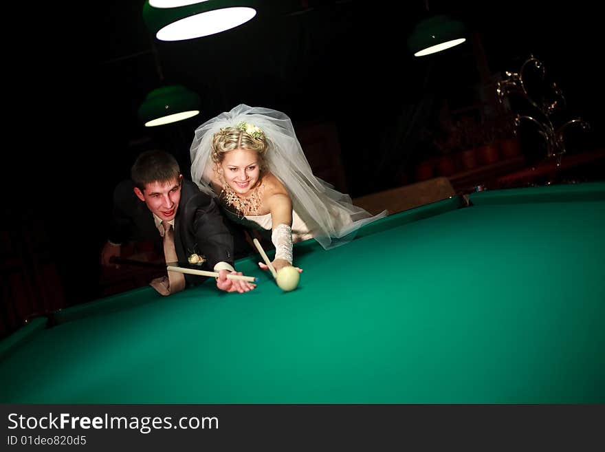 Bride and groom play billiard