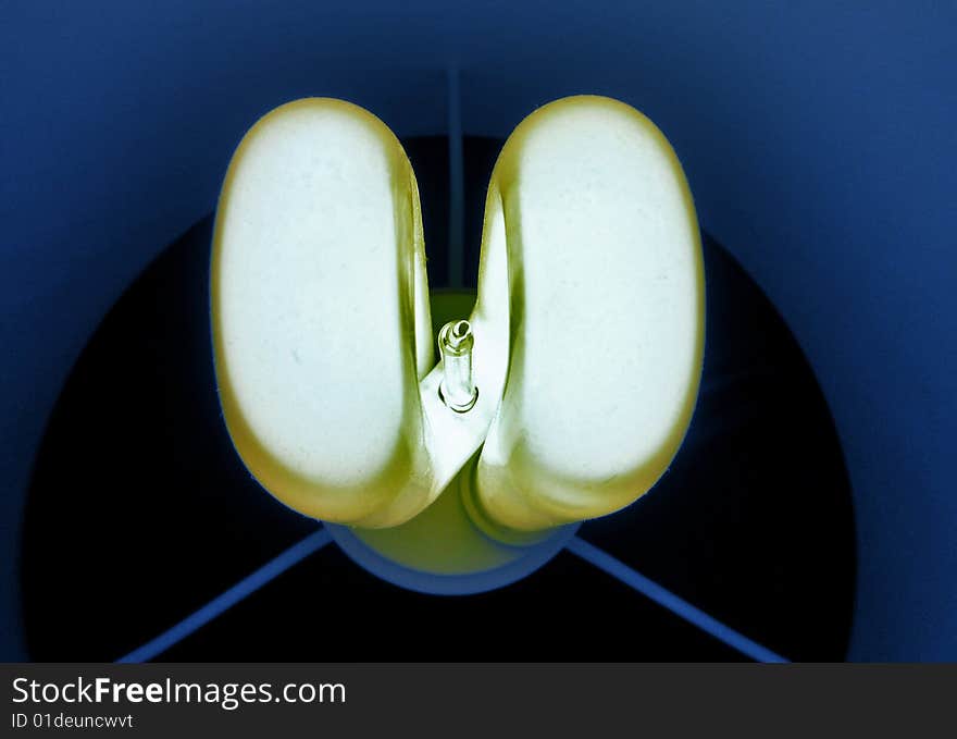 An energy saving light bulb on a dark green background. An energy saving light bulb on a dark green background.