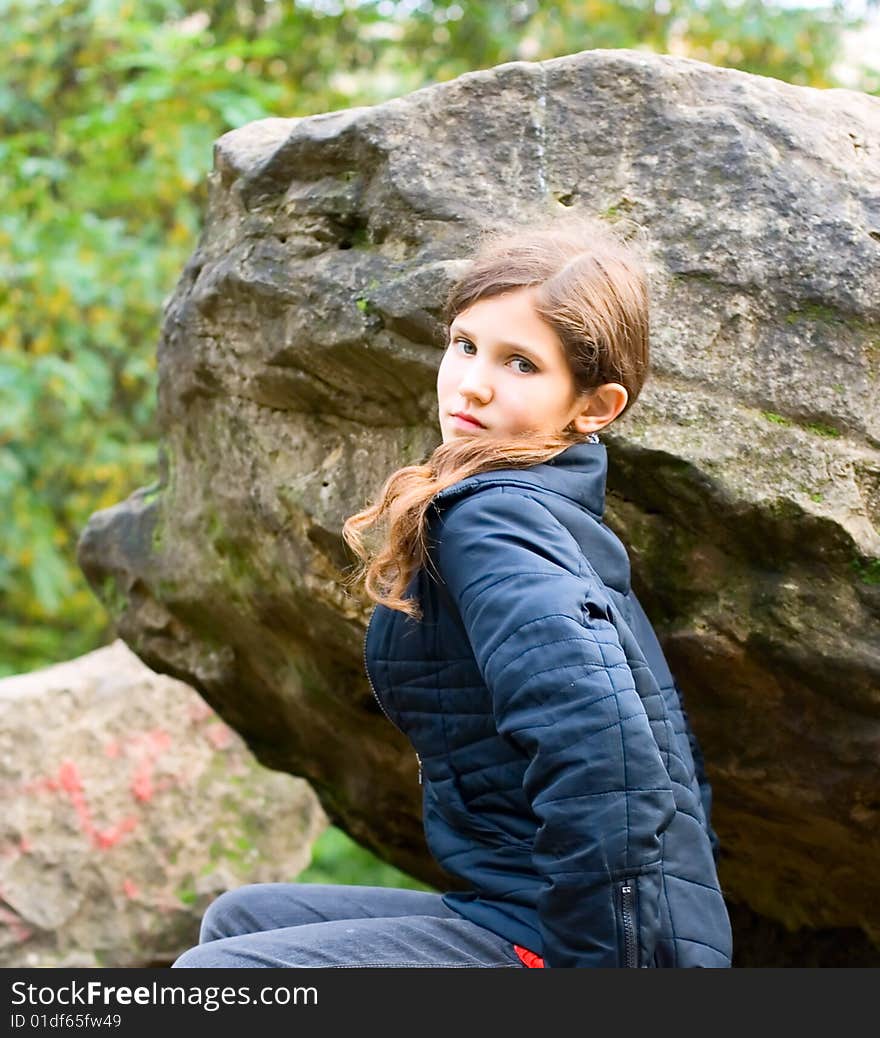 Portrait teen girl on big stone in park