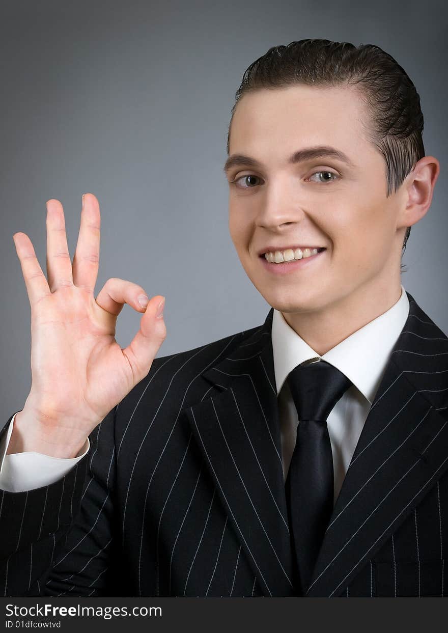 Young smiling businessman giving okay sign. Young smiling businessman giving okay sign