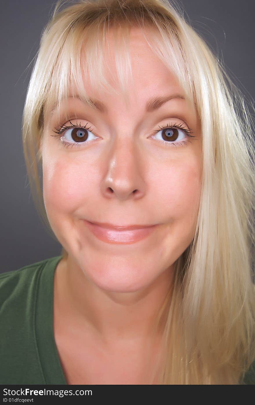 Beautiful Blond Woman with Funny Face against a Grey Background