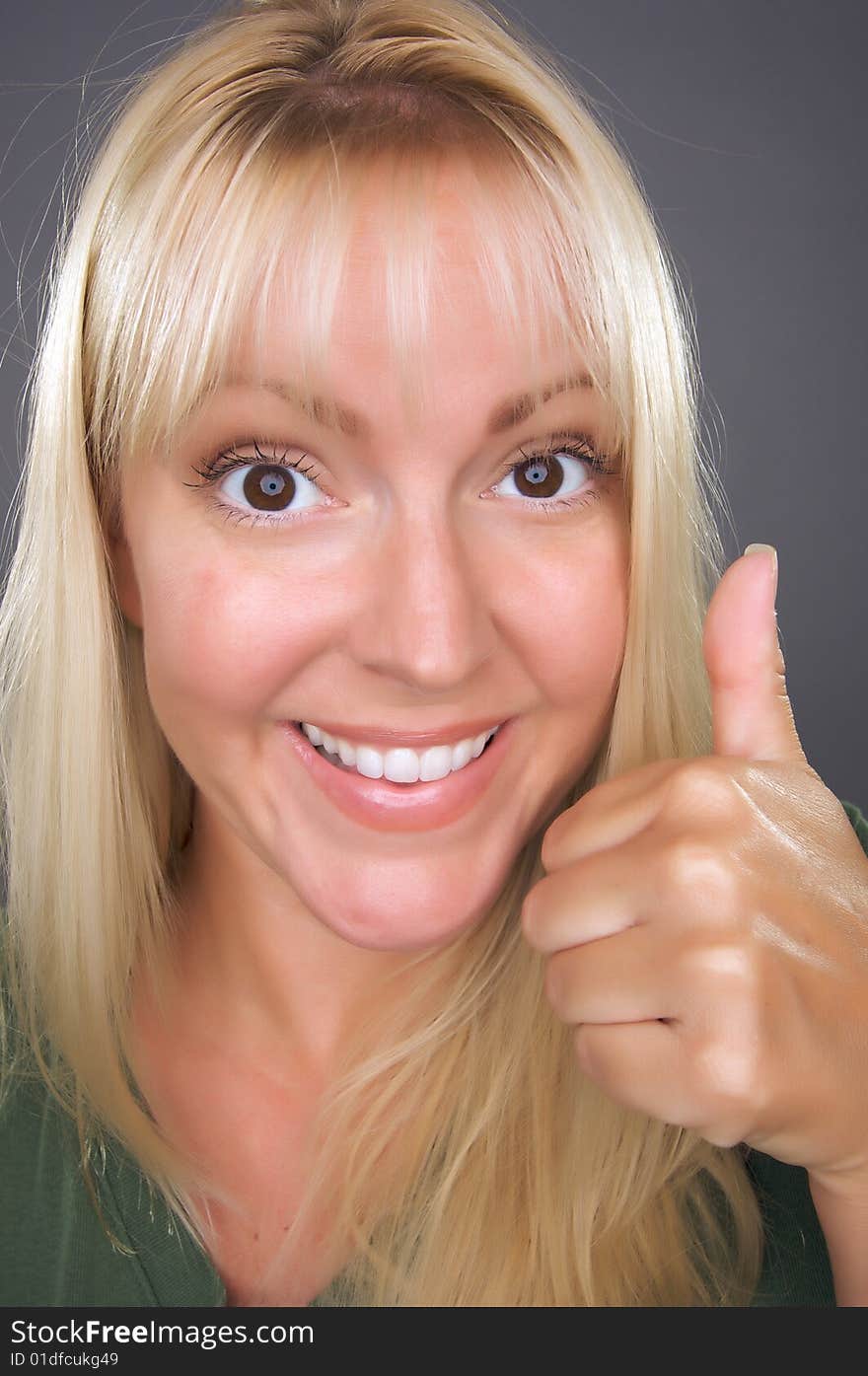 Beautiful Woman with a Thumbs Up Against a Grey Background.