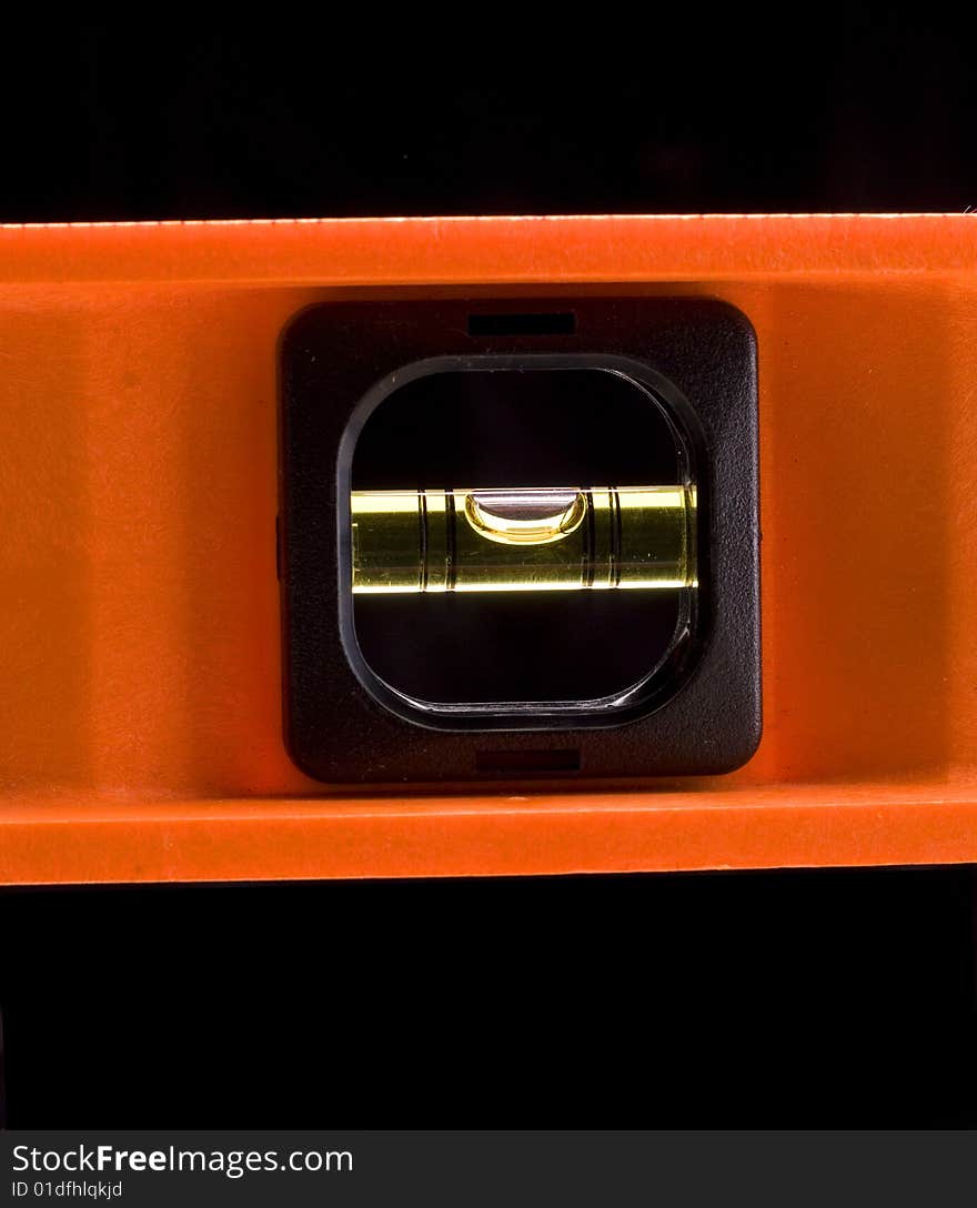 Orange spirit level against a black background