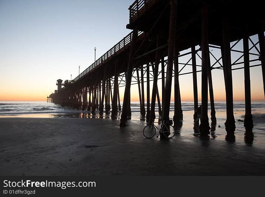 A pier on the coast of Southern California silhouetted against a sunset. A pier on the coast of Southern California silhouetted against a sunset.