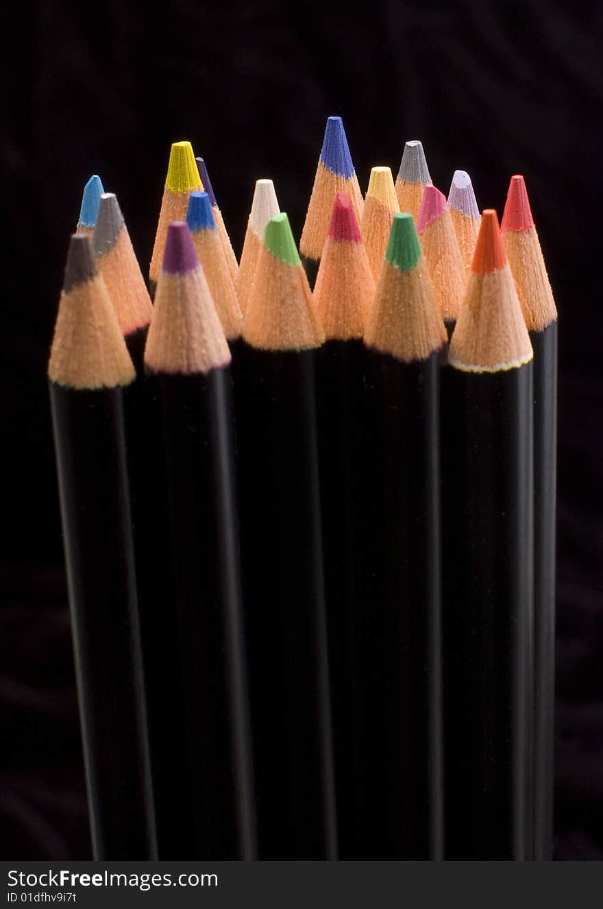 Colored pencils lined up on a black background